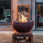 Close up of Corten Steel Seare Bole Plancha Grill with log store behind