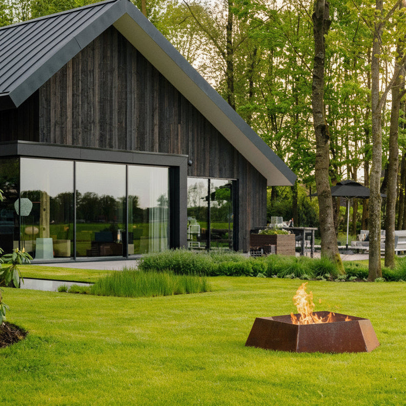 Corten steel hexagonal Forma fire bowl in a garden outside a log cabin 