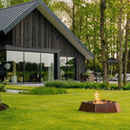 Corten steel hexagonal Forma fire bowl in a garden outside a log cabin 