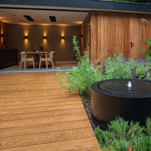 Aluminium circular water table in garden with decking