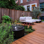 Aluminium circular water table in a modern urban garden with decking and lounge furniture