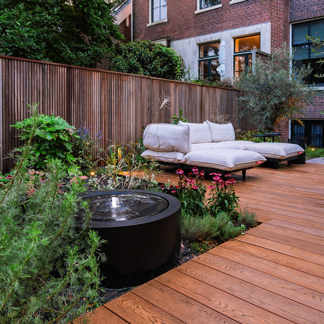 Aluminium circular water table in a modern urban garden with decking and lounge furniture