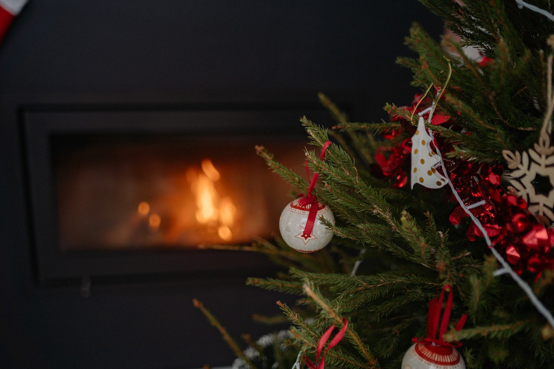 A festive Christmas tree adorned with ornaments and ribbons, perfect for gifts for gardeners, with a warm fireplace in the background